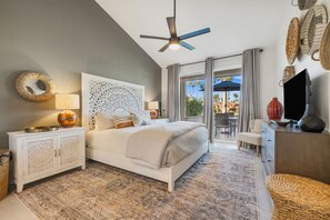 A bedroom with a bed, a ceiling fan, a TV, and a view of the outdoors. - Stunning, Fully Remodeled 2-Bed/2-Bath Residence in Serene Palm Desert (Palm Desert)
