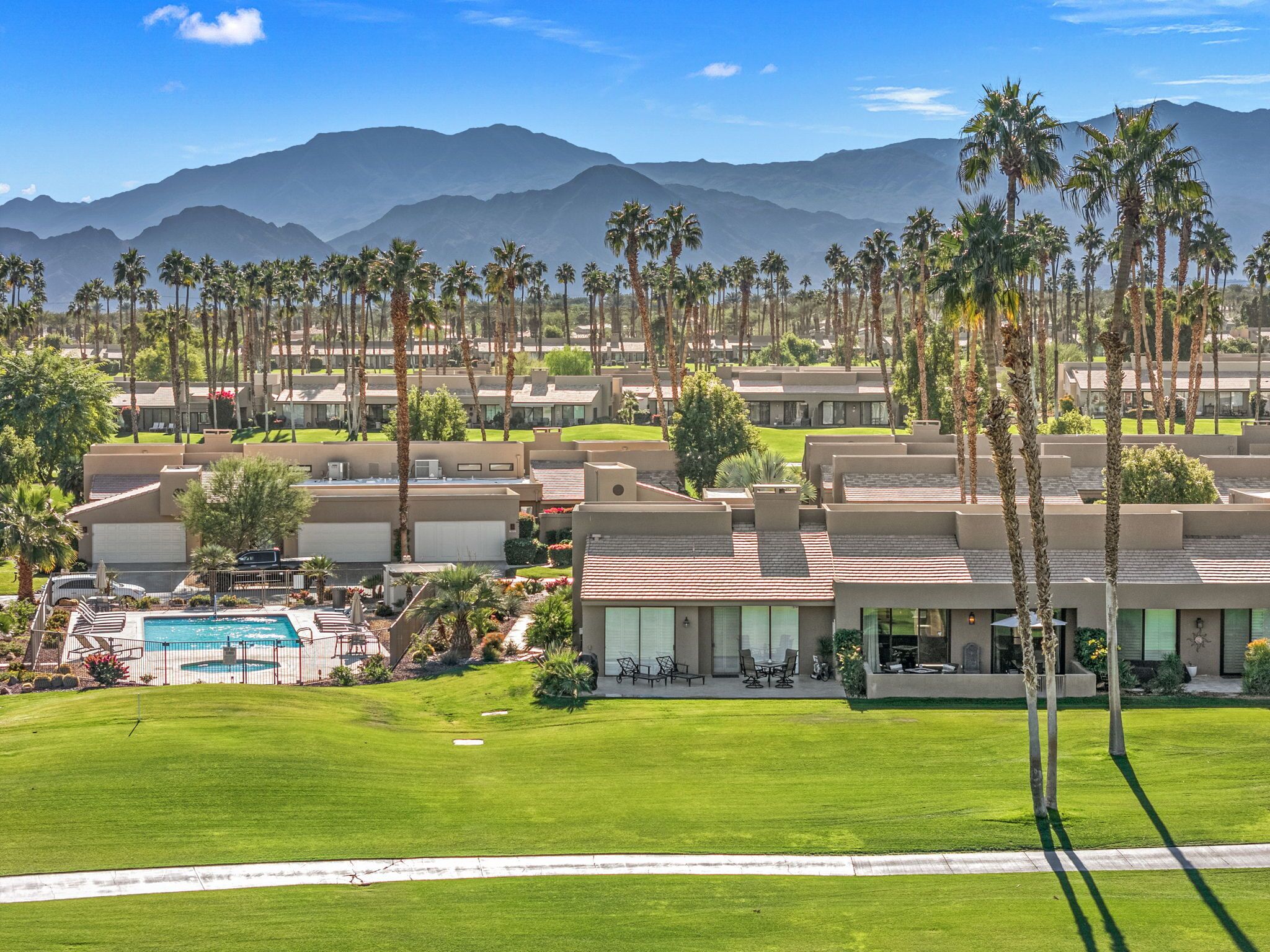 A resort with multiple buildings, a swimming pool, and palm trees.