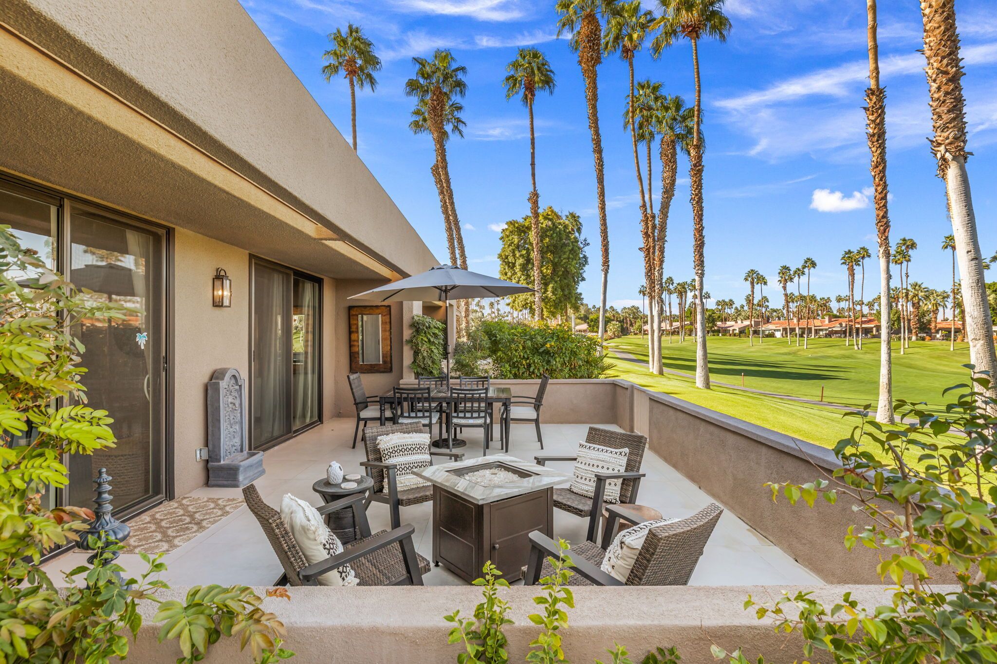 Une terrasse avec mobilier d’extérieur, un foyer et une vue sur un terrain de golf.