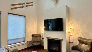 A modern living room with a fireplace, a mounted TV, and a ski rack. - Peaceful 2-bedroom house in charming Seeley Lake (Seeley Lake)