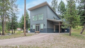 A modern two-story house with a covered porch and a gravel driveway. - Peaceful 2-bedroom house in charming Seeley Lake (Seeley Lake)