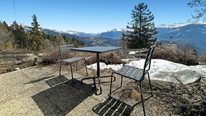 Un área de estar al aire libre con una mesa y sillas, con vistas a un paisaje montañoso.