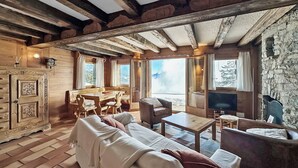 Un acogedor interior de cabaña de troncos con sofá, mesa de comedor y sillas.