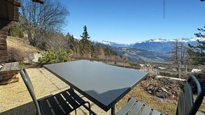 Une table et des chaises disposées à l’extérieur, avec une vue sur la montagne.