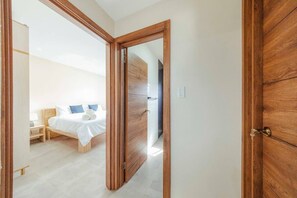 A bedroom with a wooden door, a bed with white bedding, and a nightstand. - Pool&Jacuzzi 18 Guests Complex Sea La Vie 10Br|5Ba (aruba)