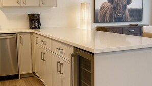Eine moderne Küche mit hellen Schränken, einem eingebauten Backofen und einer Kaffeemaschine auf der Arbeitsplatte.