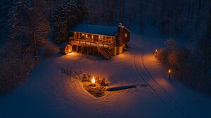 Schneebedeckte Landschaft mit einem Haus, das einen Balkon und einen Kamin besitzt.