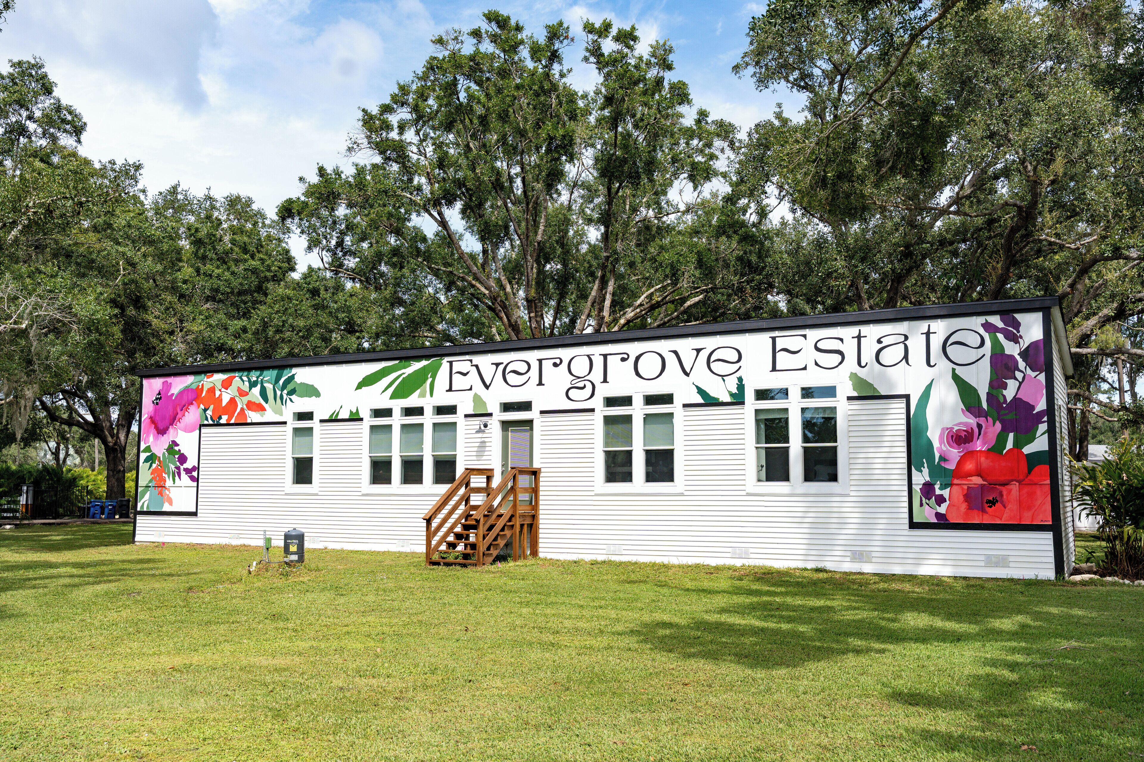 Ein weißes Gebäude mit der Aufschrift "Evergrove Estate", umgeben von Bäumen.