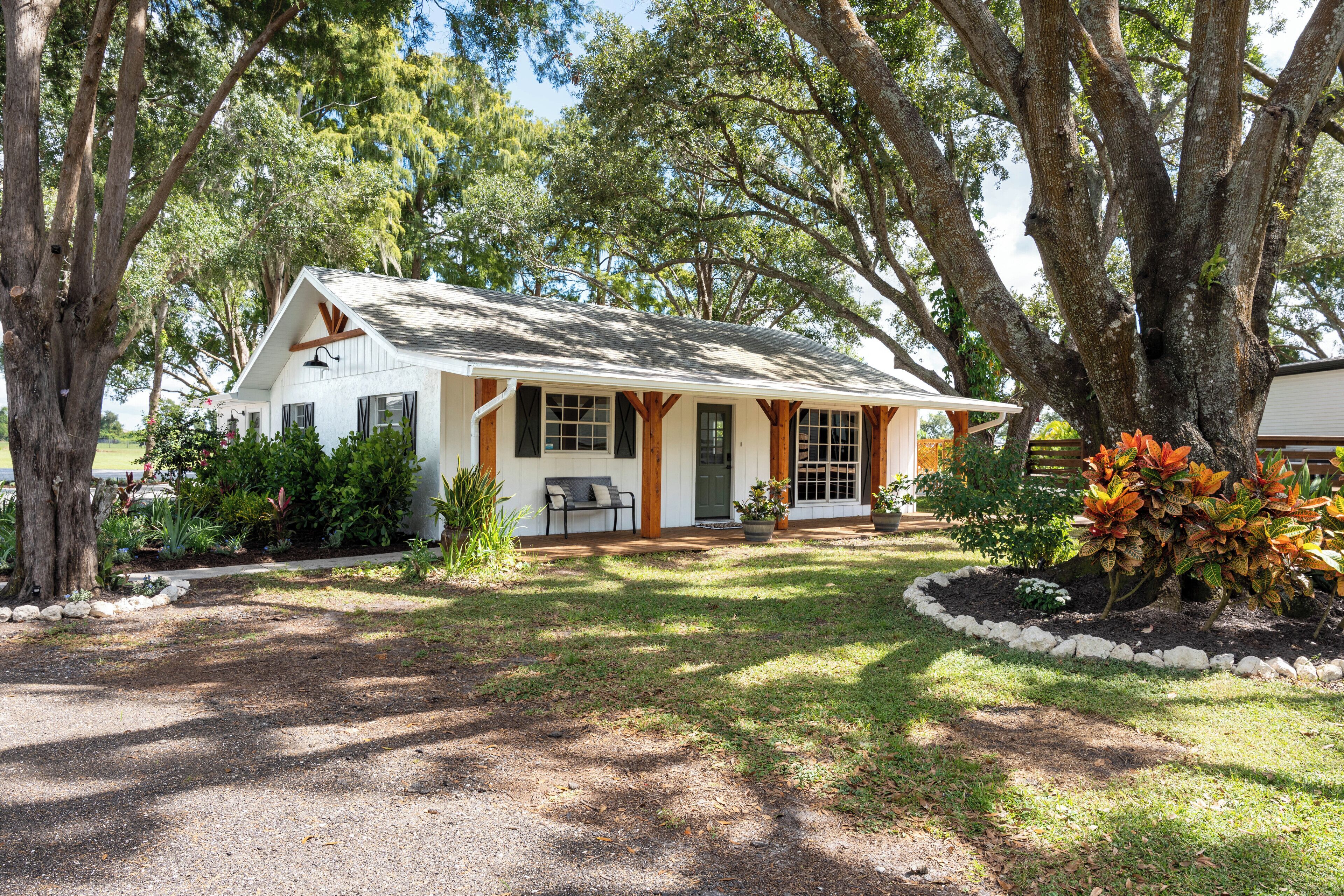 A single-story house with a front porch, surrounded by trees and a well-maintained lawn.