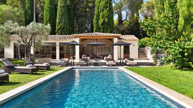 A pool area with lounge chairs and umbrellas, surrounded by greenery and tall trees. - Bastide of the Rose Comtesse – The Art of Intimate Luxury in Provence (Ventabren)