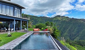 Ein modernes Haus mit Pool mit Blick auf eine gebirgige Landschaft.