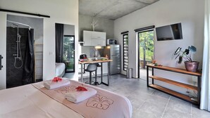 A modern hotel room with a bed, a shower, a kitchenette, and a TV. - Moorea Horizon – Stunning Panoramic View – Pool (Papeete)