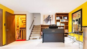 A home office with a KAWAI desk, a bookshelf, and a staircase.