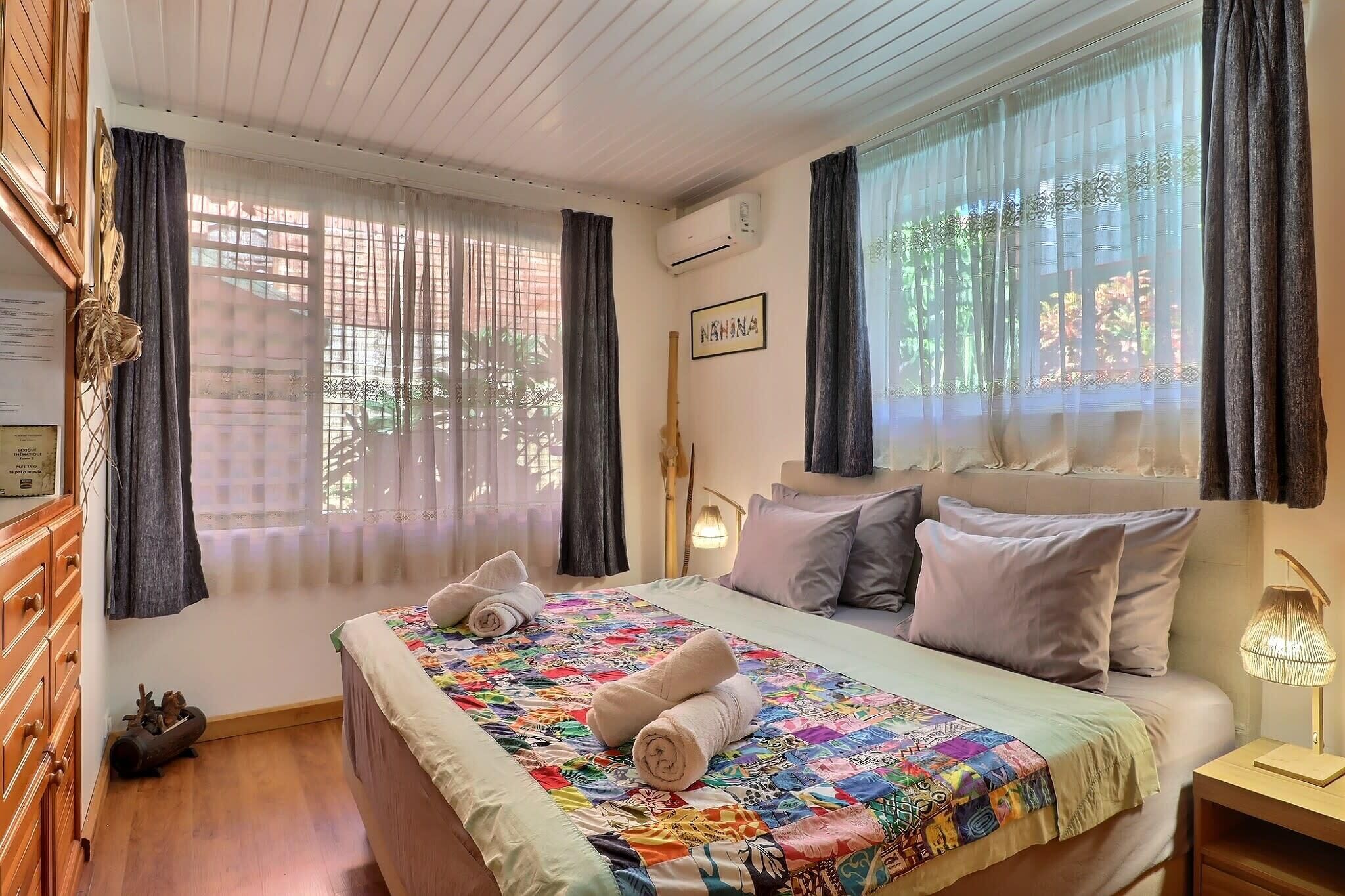 A neatly arranged hotel room with a bed, a bedside lamp, and a window with curtains.