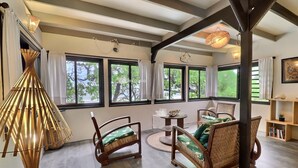 Una habitación amplia con ventanas grandes, muebles de madera y una mesa redonda.