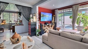 Ein modernes Wohnzimmer mit einer Couch, einem Fernseher und einem Esstisch mit Dekoration.
