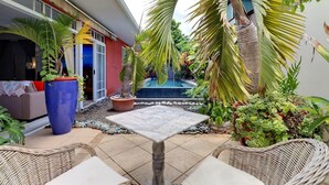 Eine Terrasse mit einem Marmor-Tisch, Korbstühlen, Topfpflanzen und einem kleinen Pool.