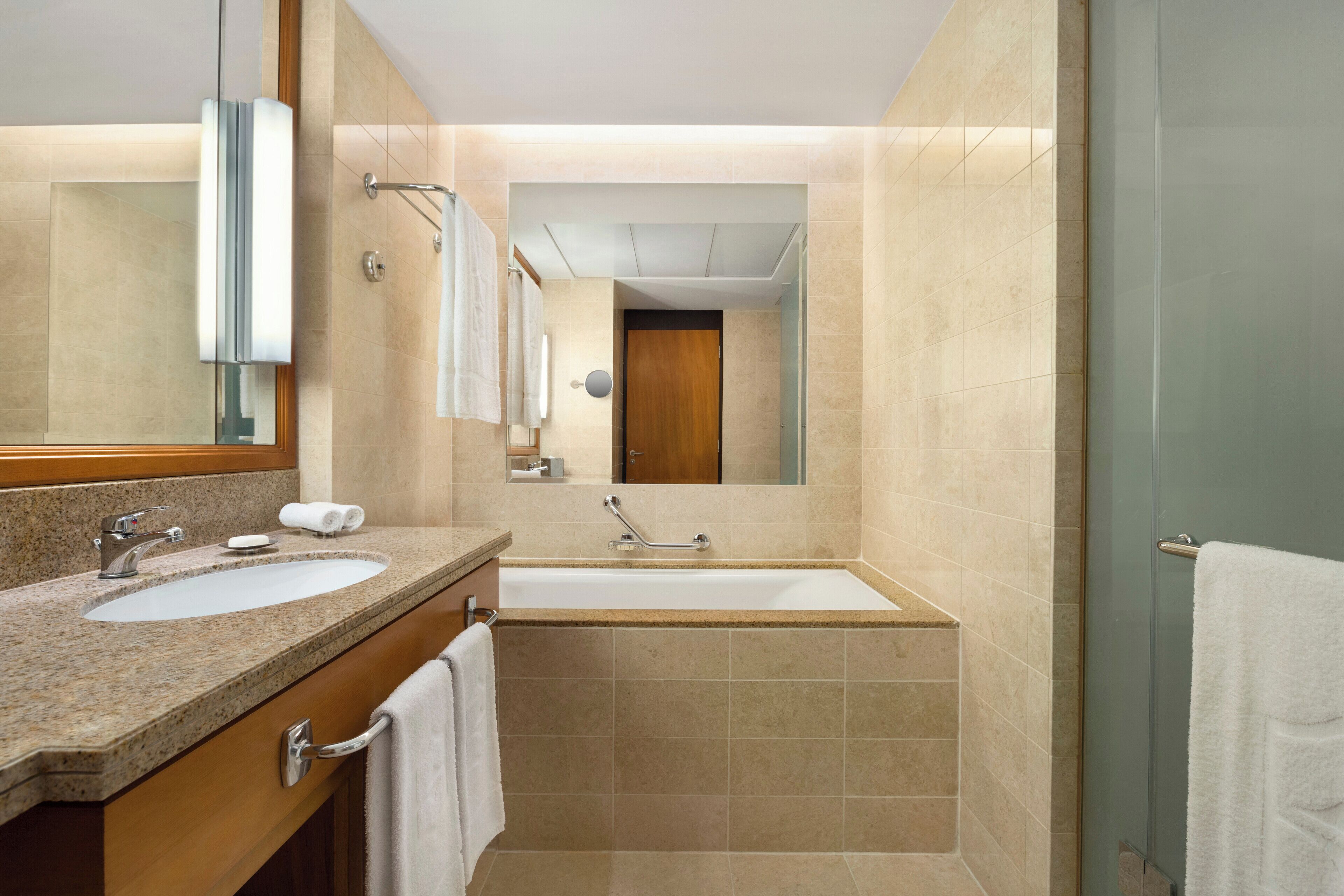 A modern bathroom with two sinks, a bathtub, and a large mirror.