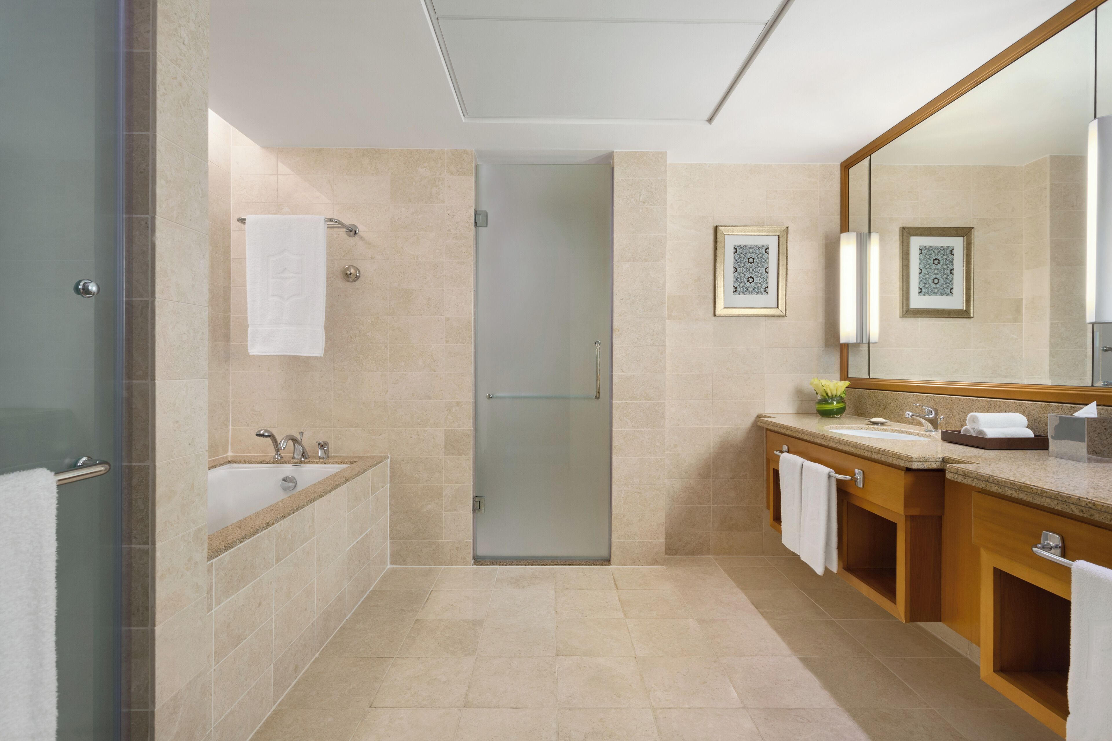 A modern bathroom with a glass shower enclosure, a bathtub, a sink with a vanity, and a large mirror.