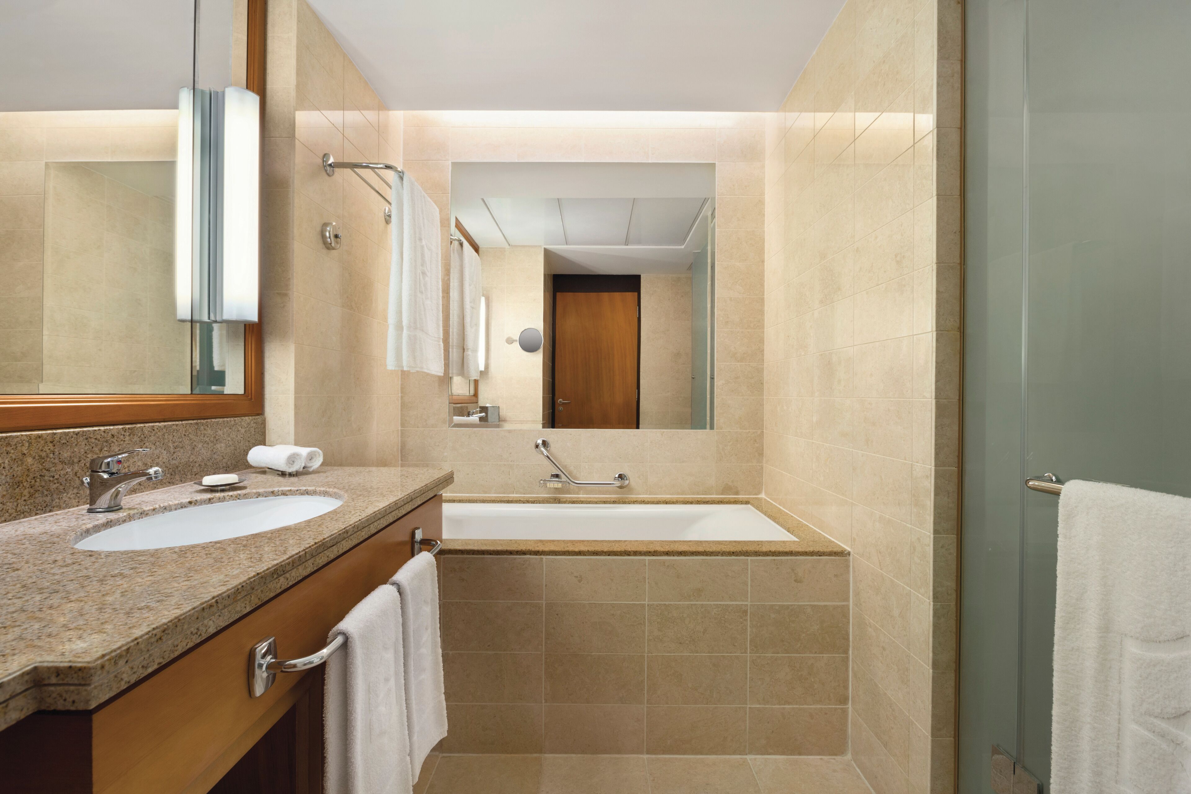 A modern bathroom with two sinks, a bathtub, and a large mirror.