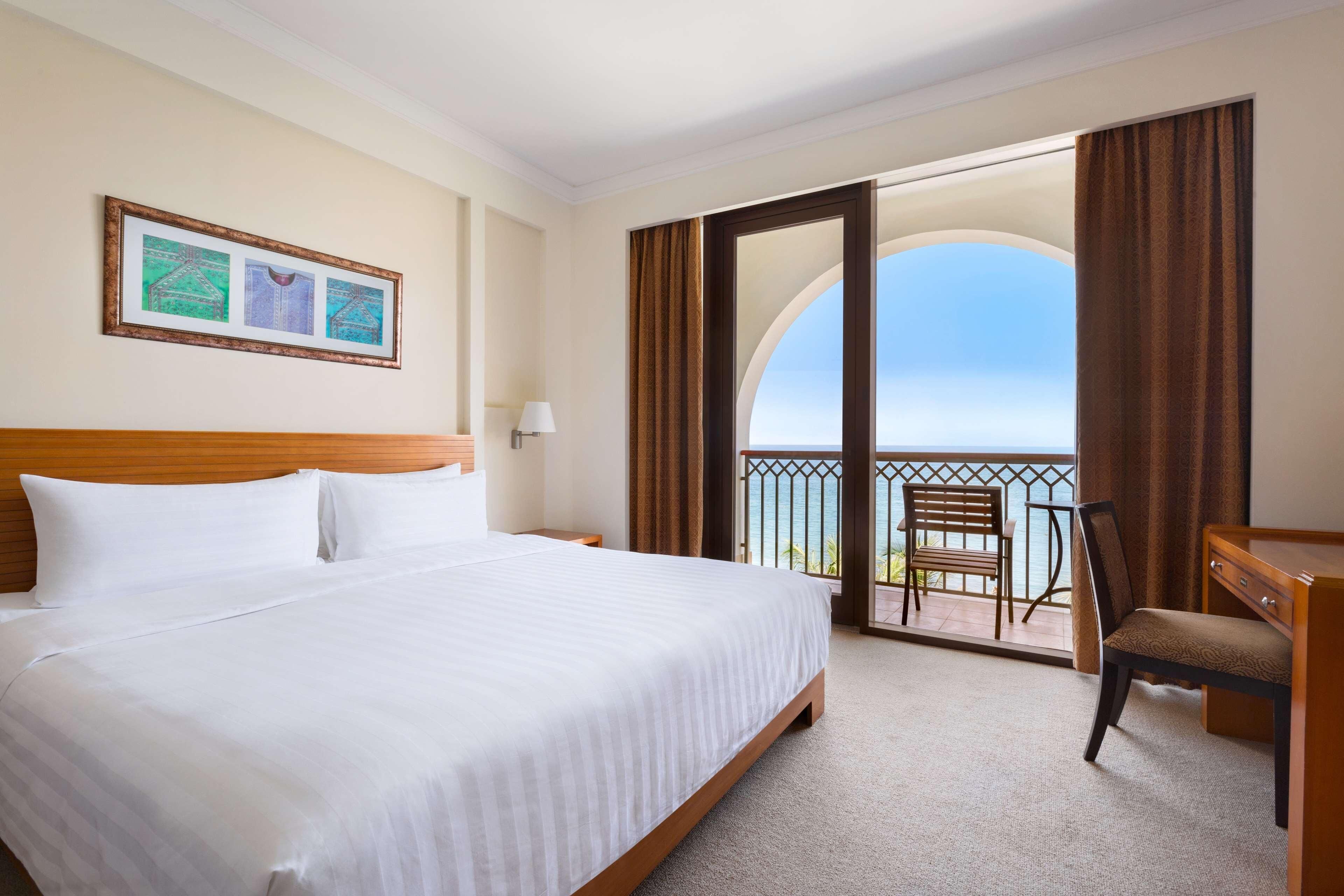 Une chambre d’hôtel avec un grand lit, un bureau, une chaise et un balcon avec vue.