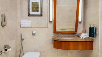Un baño con inodoro, lavamanos, espejo, una obra de arte enmarcada y un perchero para toallas.