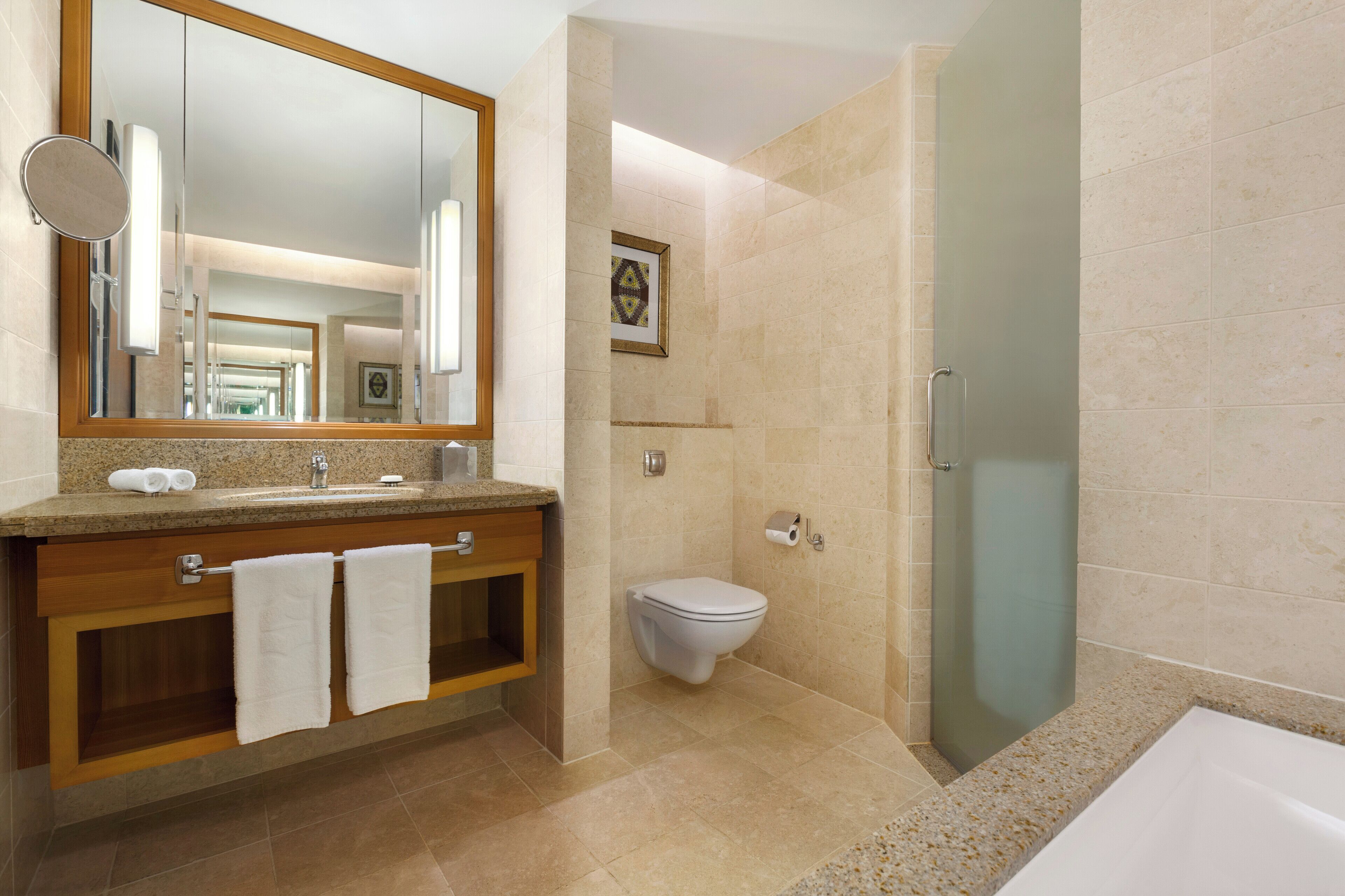 A modern bathroom with a large mirror, a sink, a toilet, and a glass-enclosed shower.