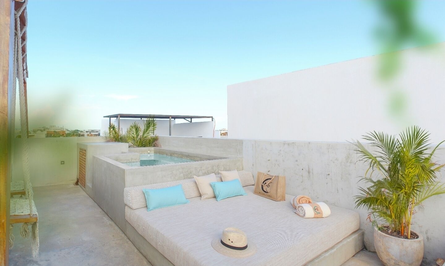 A rooftop terrace with a seating area, a hot tub, and potted plants.