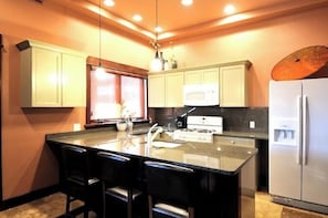 Una cocina con una isla central, armarios blancos, un microondas y un refrigerador.