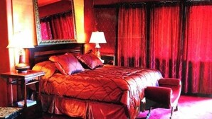 Une chambre d’hôtel avec un grand lit, deux lampes de chevet, une chaise et un miroir au mur.