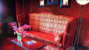 Un canapé rouge à motifs, avec une petite table et un vase placés devant.