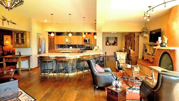 A spacious living area with a central island, bar stools, and a fireplace. - A touch of the wild west and the loving touch of the pioneer  (Bigfork)