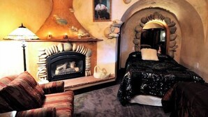 Quarto aconchegante com lareira, uma cama e um arco de pedra.