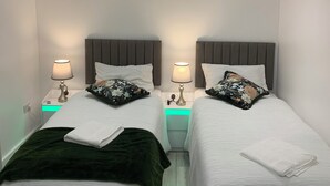 Hotellihuone, jossa on kaksi sänkyä, ja jokaisessa sängyssä on tyyny ja yöpöytälamppu.