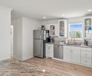 A modern kitchen with white cabinetry, stainless steel appliances, and a granite countertop. - Marvelous 4-bedroom Oceanfront home in Harbor Island (Harbor Island)
