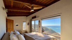 Un dormitorio con una cama grande, un ventilador de techo y vista al océano.