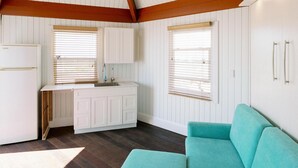 Une cuisine moderne avec des meubles blancs, un canapé de couleur turquoise et des poutres en bois au plafond.