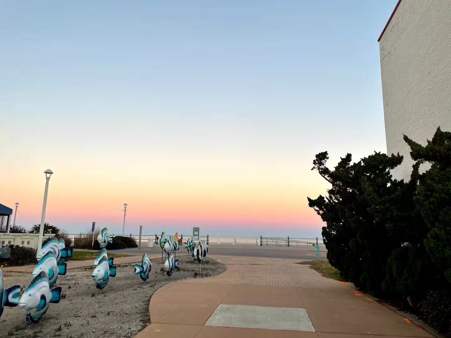A pathway lined with decorative fish sculptures leading to a beach.