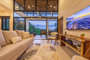 Ein modernes Wohnzimmer mit einer Couch, einem Sessel, einem Couchtisch und einem großen Fernseher, der eine malerische Aussicht zeigt.