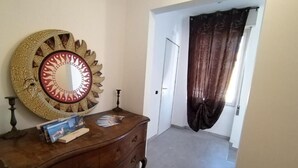 Una habitación con un aparador de madera, un espejo decorativo y una puerta que da a otra estancia.