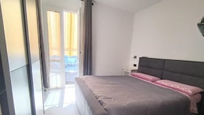 Un dormitorio con cama, mesita de noche y vistas a un balcón.