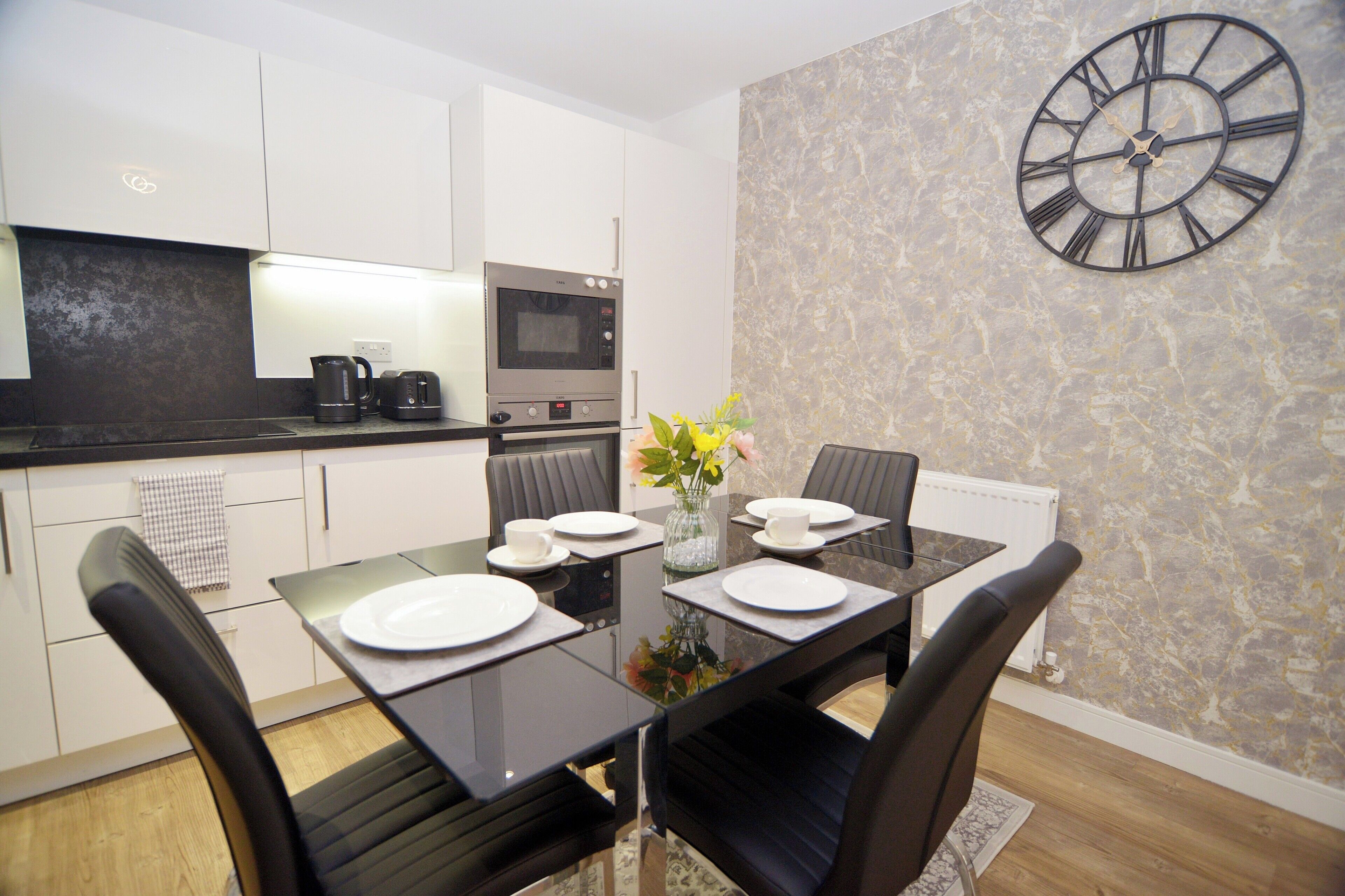 A modern kitchen with white cabinets, a built-in oven, and a coffee maker.