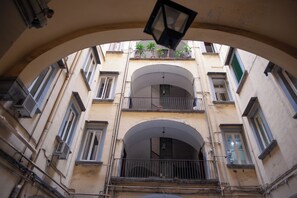 Um edifício com vários andares, varandas, janelas em arco e plantas.