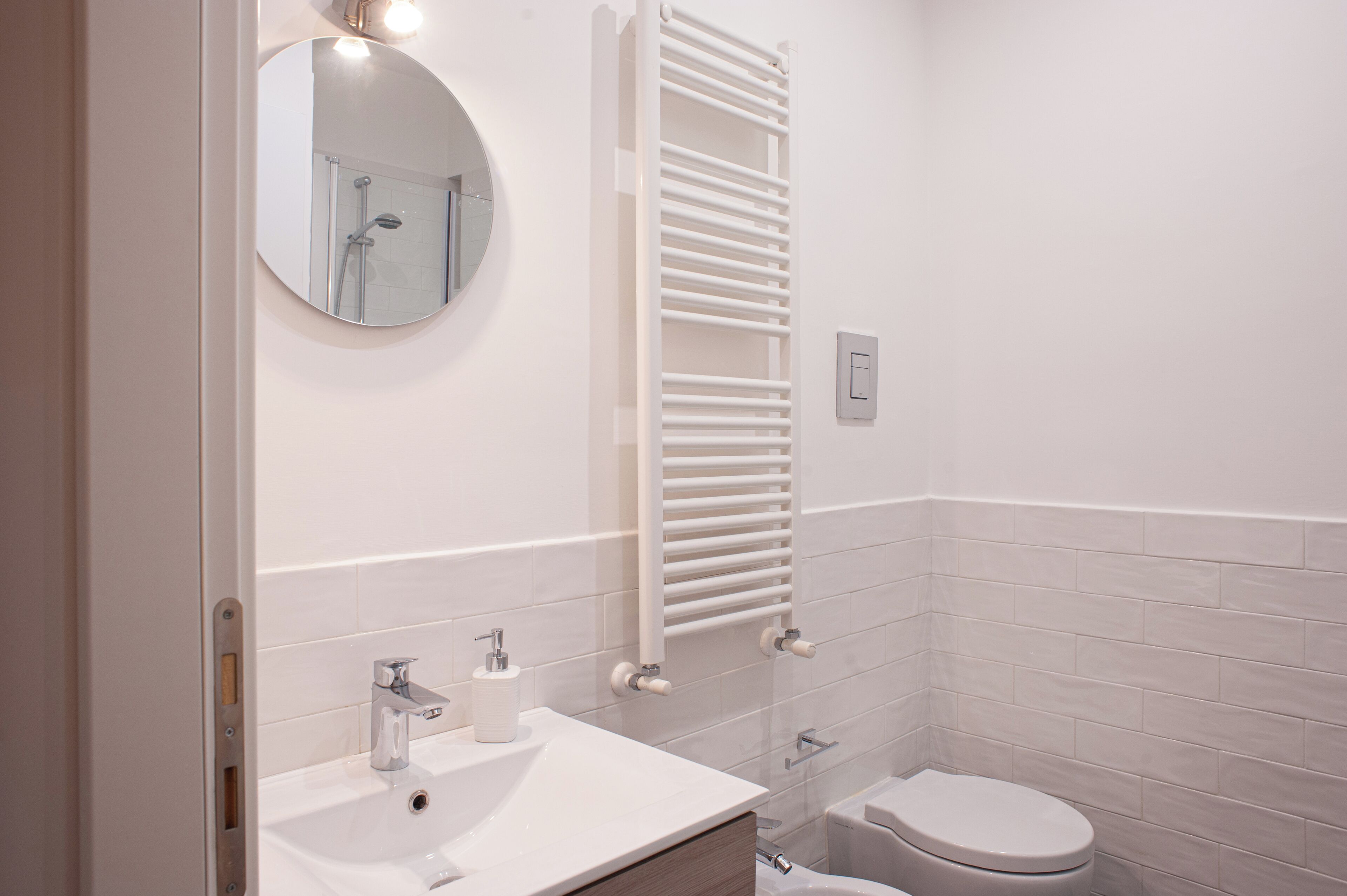 A modern bathroom with a white sink, mirror, and toilet.