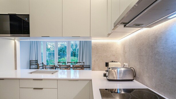 Una cocina moderna con una isla central, electrodomésticos integrados y vistas al exterior.