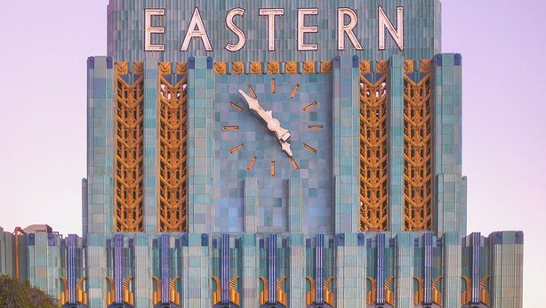 Un hotel con una piscina grande al frente, que presenta un reloj y la palabra "EASTERN" en la fachada.