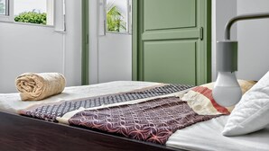 A neatly made bed with patterned bedding, a rolled towel, and a bedside lamp.