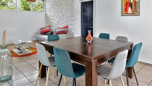 A dining area with a wooden table, teal chairs, and a stone wall.
