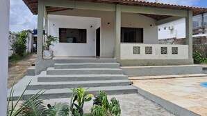 Una casa de dues plantes amb un porxo cobert i un petit jardí.