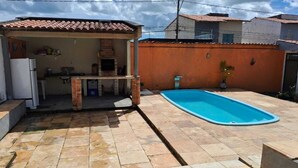 Un pati amb piscina, zona de barbacoa i cuina petita.